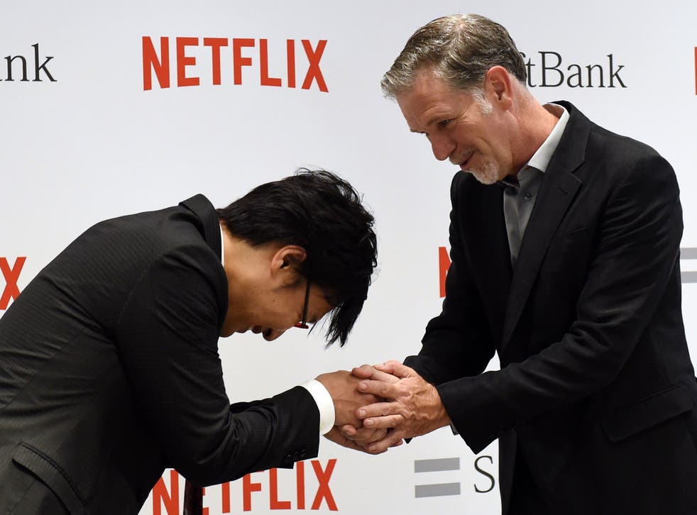 Netflix founder and CEO Reed Hastings (R) shakes hands with Japanese comedian Ryota Yamasato (L) during a photo session in the kick-off event of the Netflix business in Japan at a Softbank shop in Tokyo on September 2, 2015