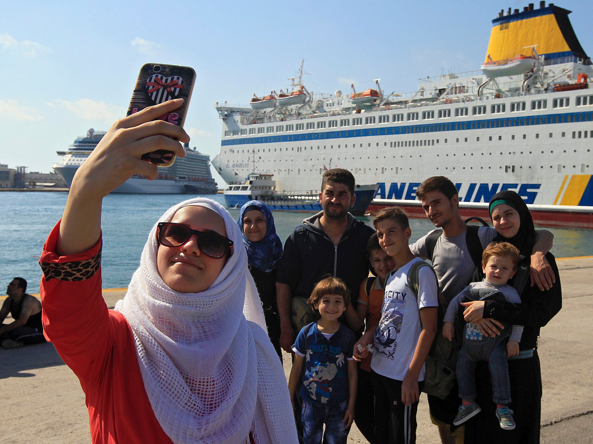 Syrian refugees take a photo after completing the next stage, a ferry from Lesbos to Piraeus