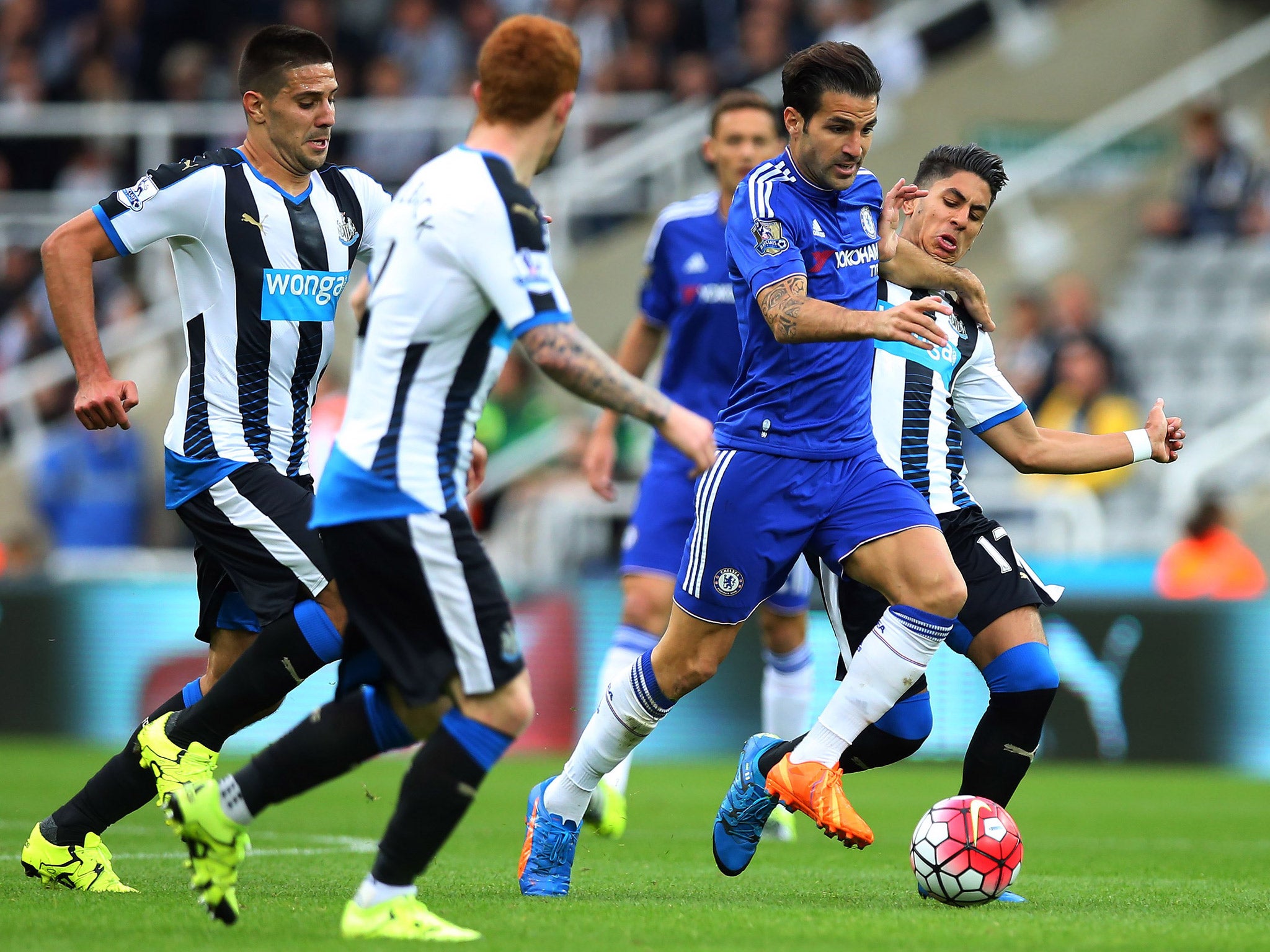 Cesc Fabregas tries to evade several Newcastle players