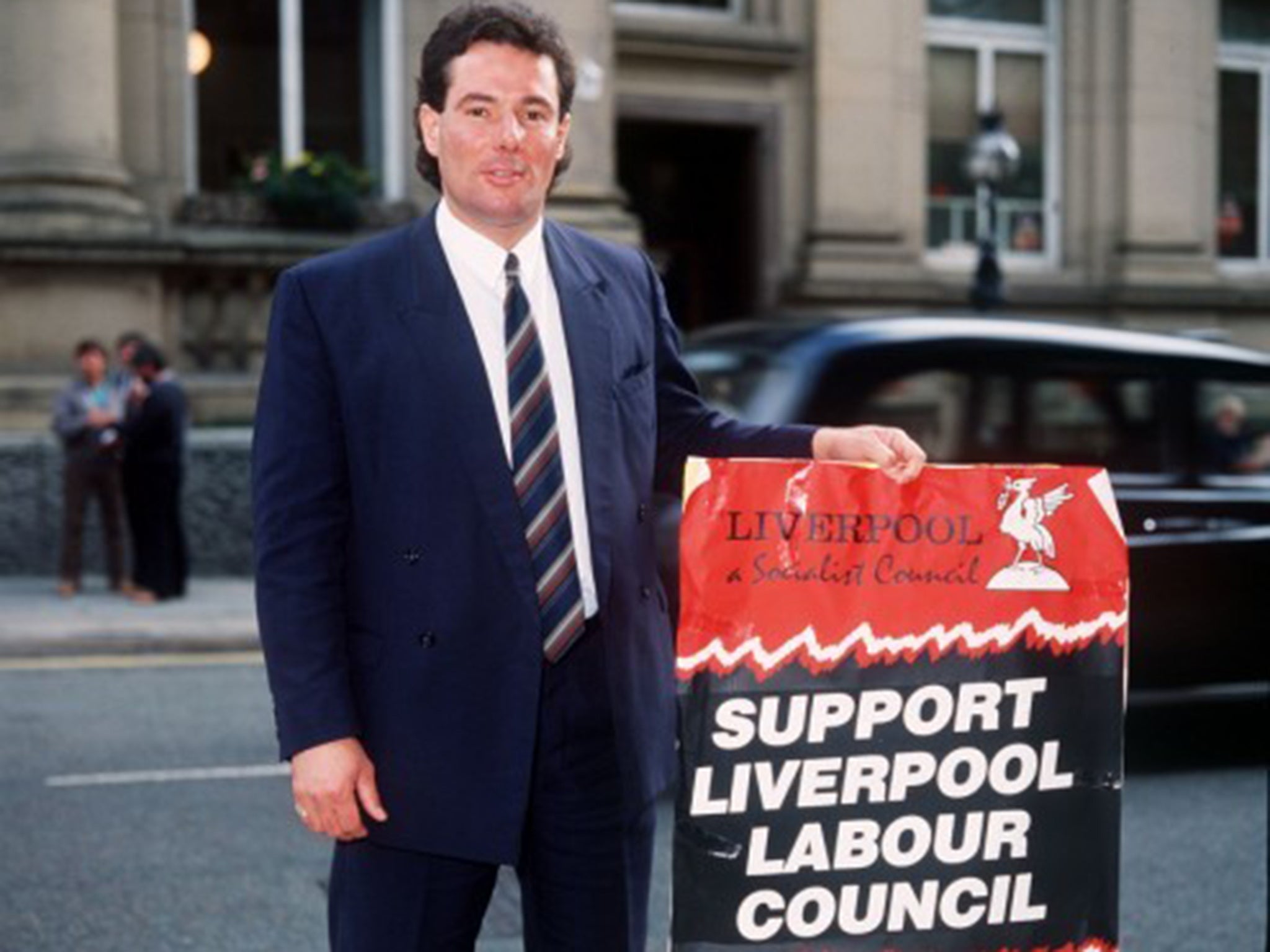 Derek Hatton Liverpool city councelor holding plackard urging people to Support Liverpool Labour Council