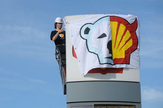 A Greenpeace activist covers the logo of the Shell oil company to protest on May 10, 2012 against the heading of the an icebreaker for Shell's Arctic oil drilling project