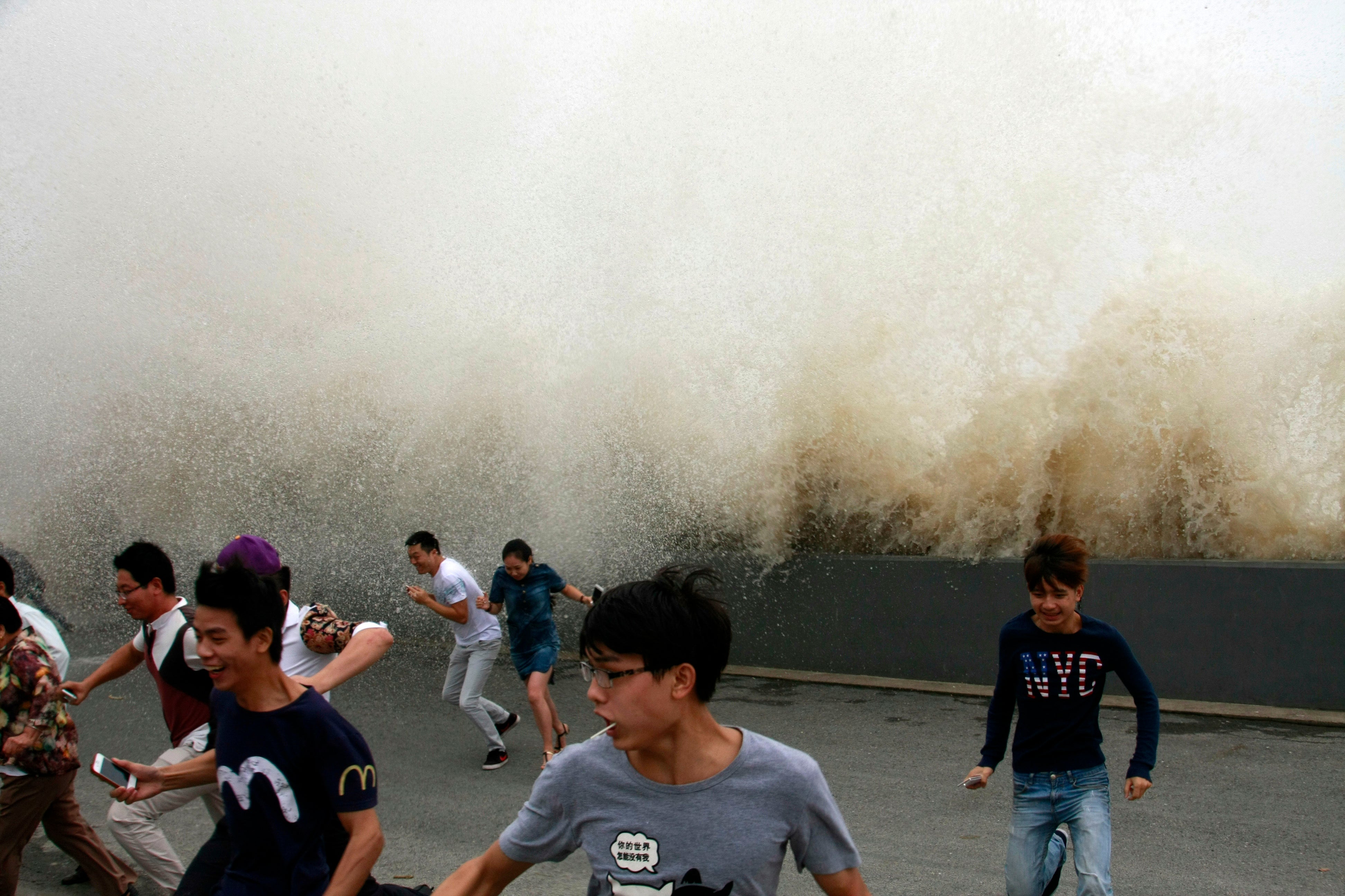Spectators run from the wall of water in Zhejiang province