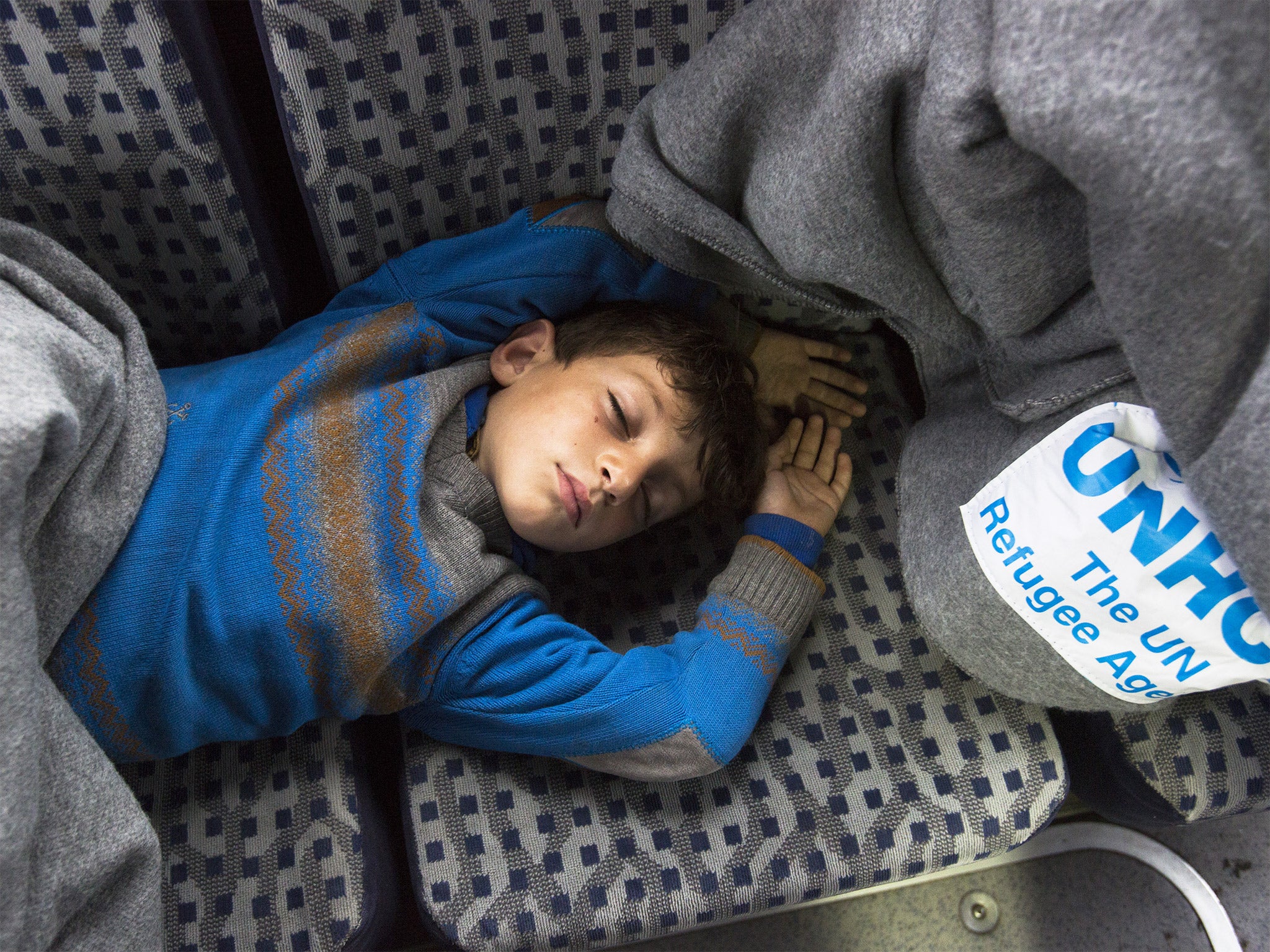 A young Syrian refugee sleeps on a bus