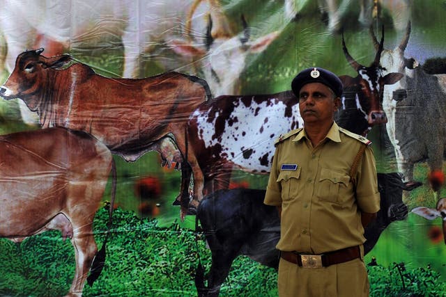 <p>An Indian policeman stands in front of a poster depicting cows as Hindus demonstrated in support of the cow slaughter ban bill passed in the Karnataka state Legislative Assembly in Bangalore on July 20, 2010.</p>