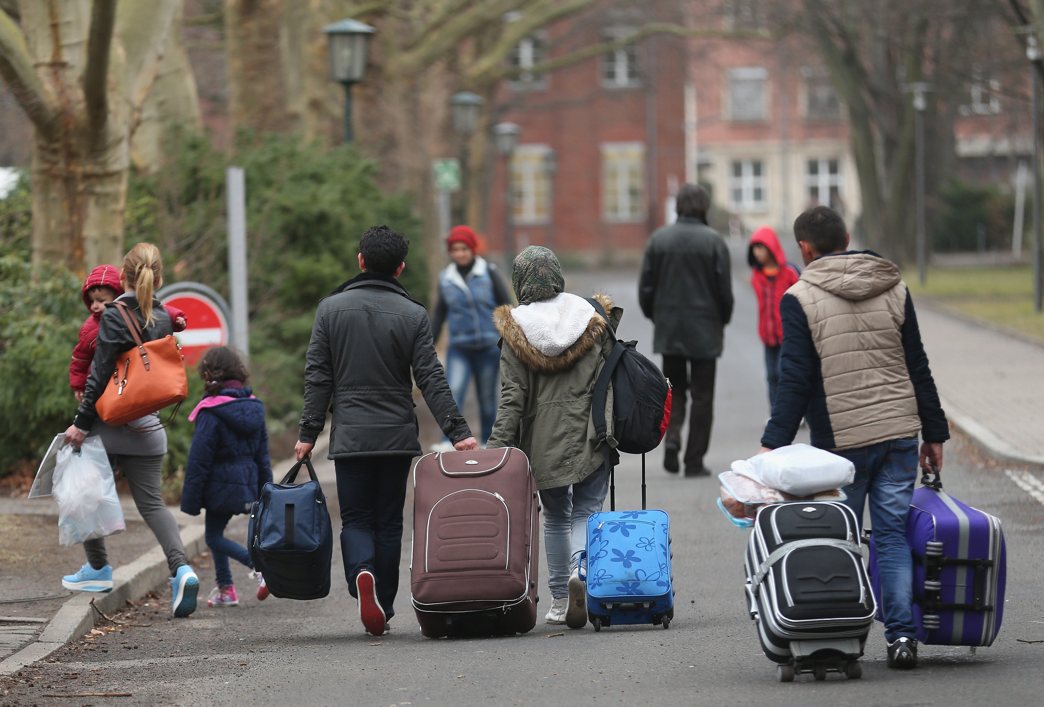 People pulling suitcases arrive at the Berlin refugee registration centre