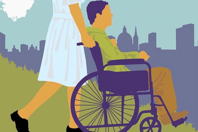 A woman pushes a man in a wheelchair through a city park
