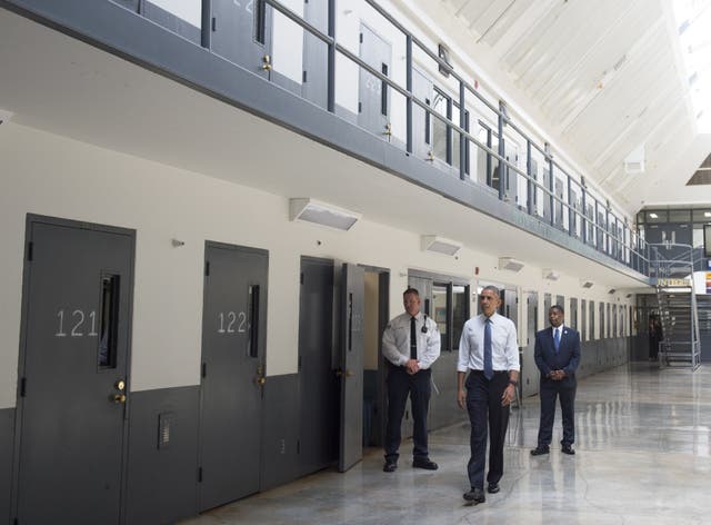 Barack Obama, alongside officer Ronald Warlick, left, and Charles Samuels, right, Bureau of Prisons Director, tours a cell block at the El Reno Federal Correctional Institution in Oklahoma.