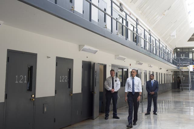 Barack Obama, alongside officer Ronald Warlick, left, and Charles Samuels, right, Bureau of Prisons Director, tours a cell block at the El Reno Federal Correctional Institution in Oklahoma.
