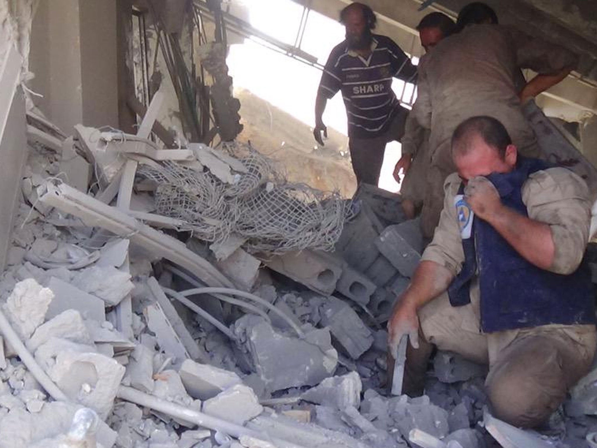 Civil defence workers in the aftermath of the Russian air strike on Talbiseh, Syria, which killed dozens of civilians