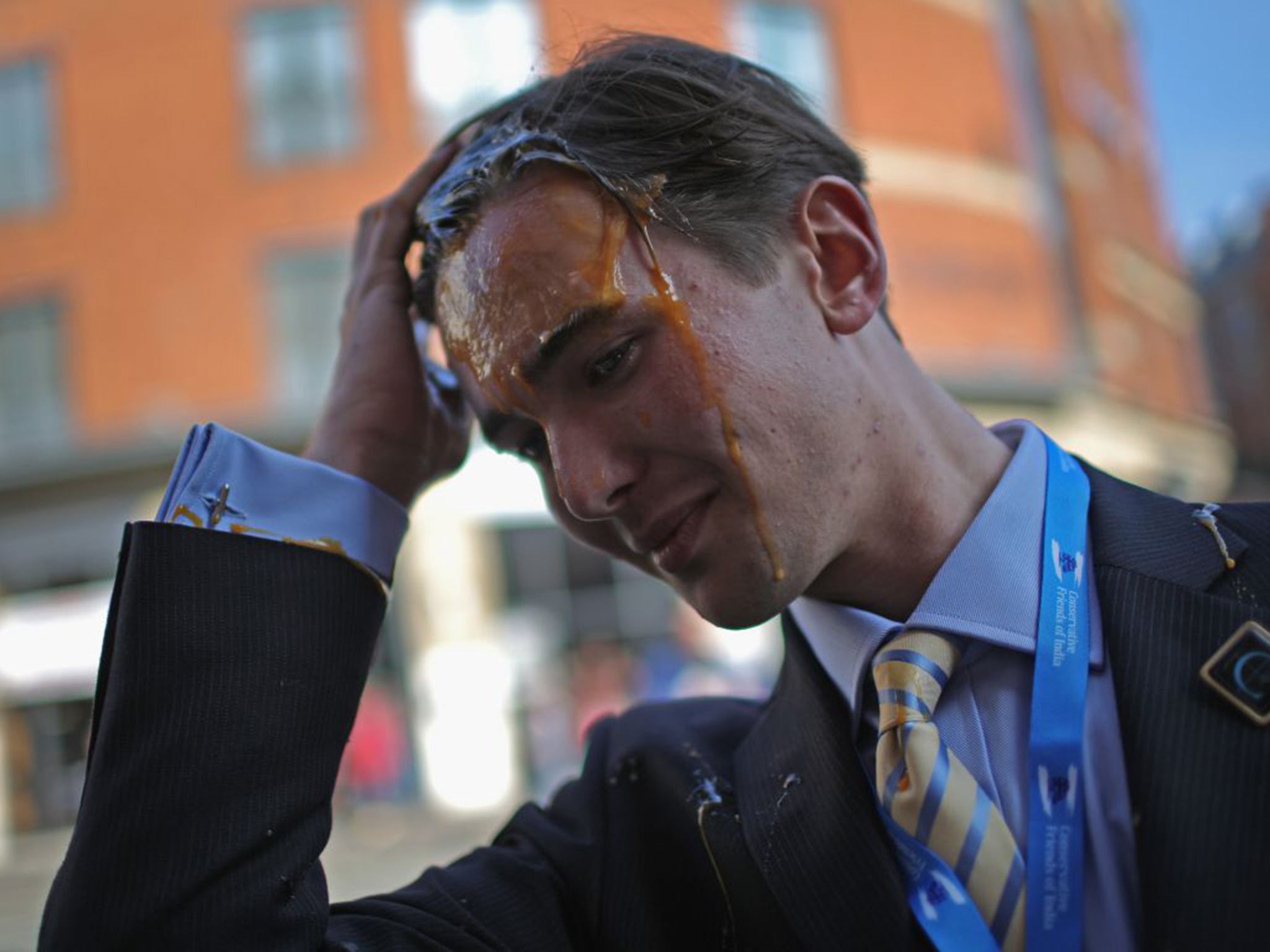 A young Tory delegate is hit by an egg as he arrives for the first day of the Conservative Party Autumn Conference 2015 on October 4, 2015