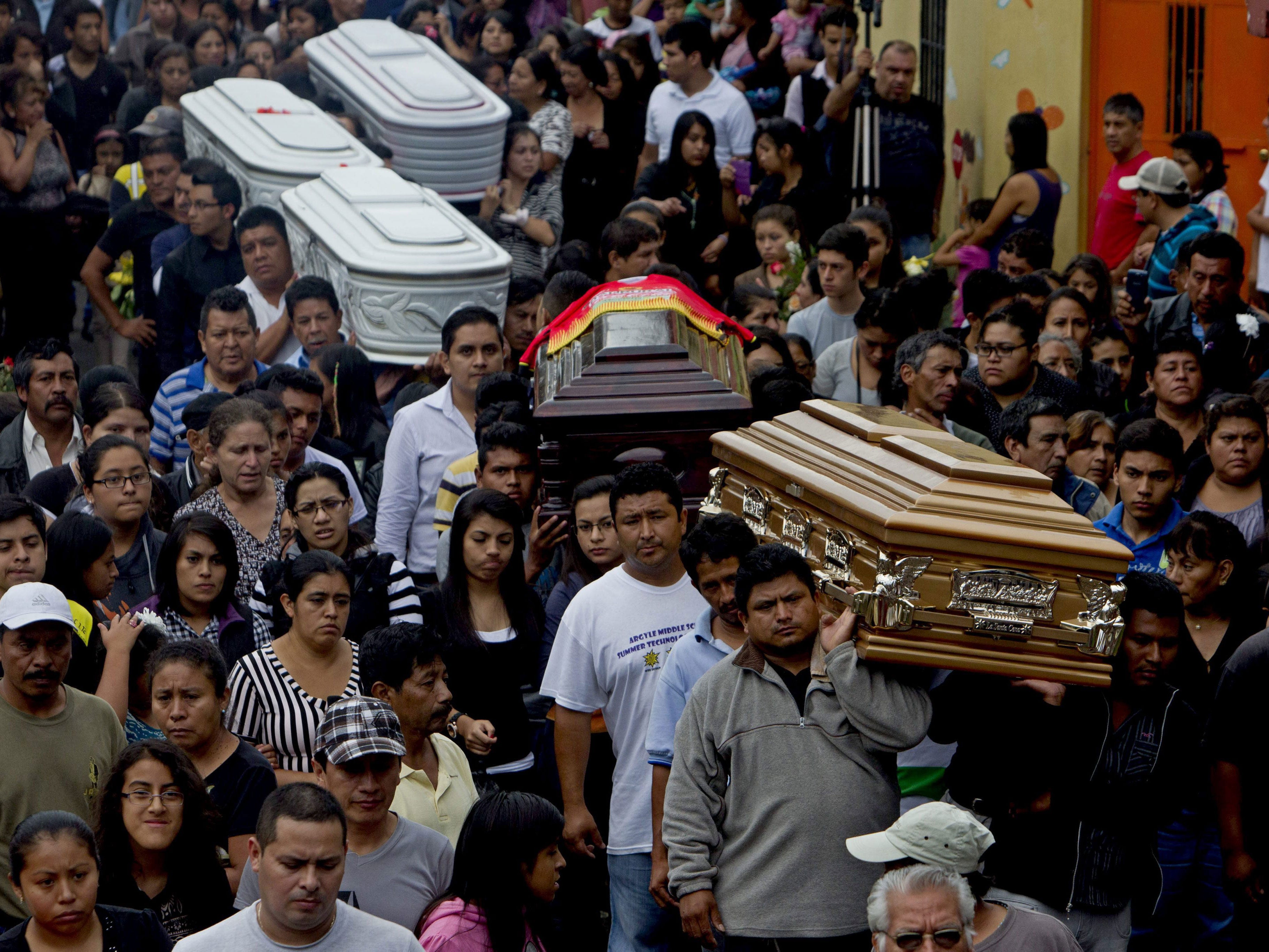 People and relatives attend the funeral of the victims of a landslide