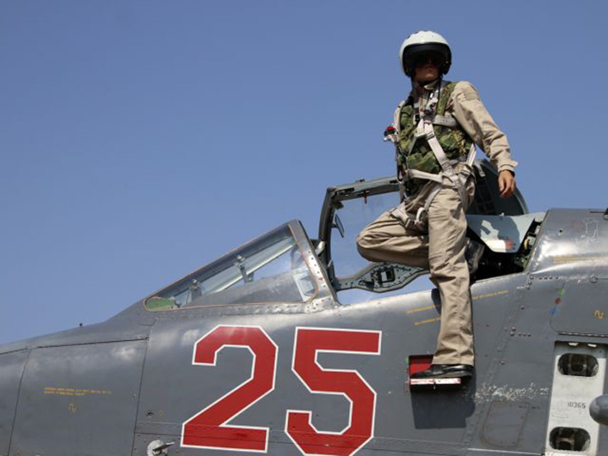 A Russian pilot climbs from an SU-25M jet fighter at Hmeimim airbase in Syria