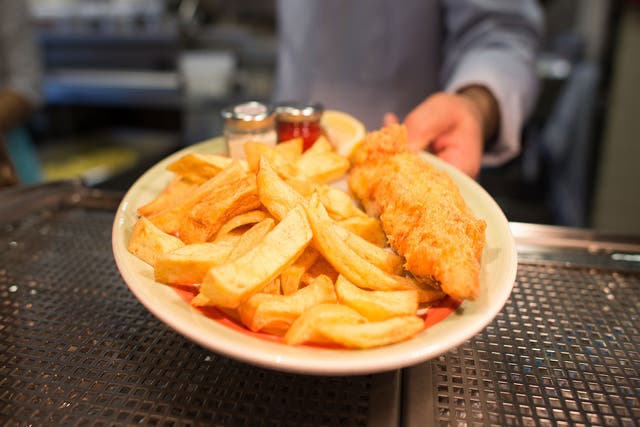 A chef with a plate of fish and chips at Poppies fish and chip restaurant in east London