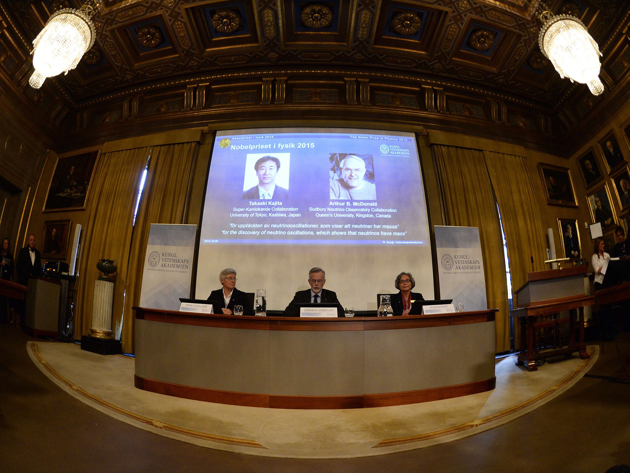 Members of the Nobel Committee for Physics, sit in front of a screen displaying the winners of the Nobel Prize in Physics 2015 Takaaki Kajita (L) and Arthur B McDonald