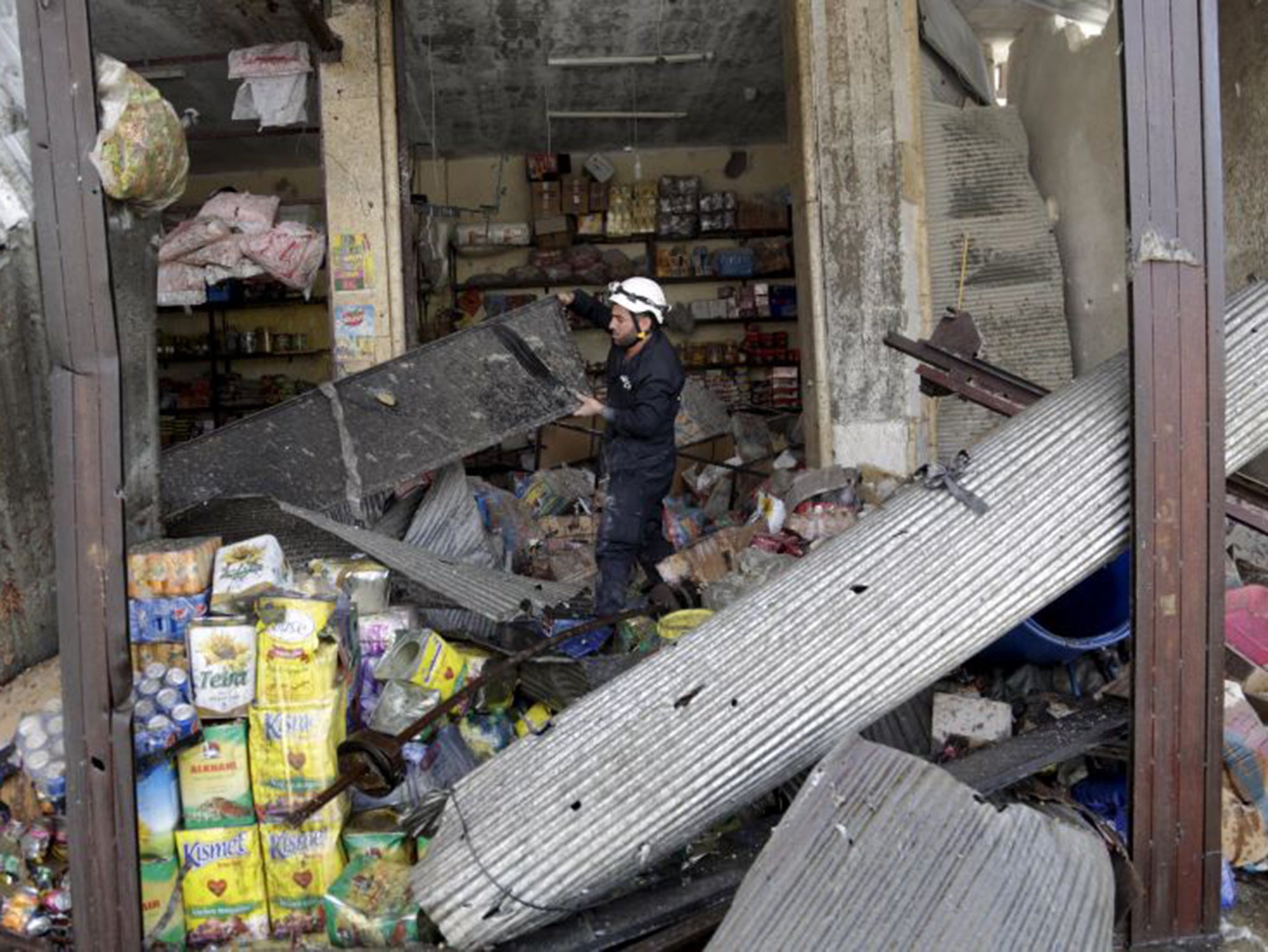 A civil defence member looks for survivors in a damaged shop at a site hit by what activists said was an air strike by forces of Syria's President Bashar al-Assad,