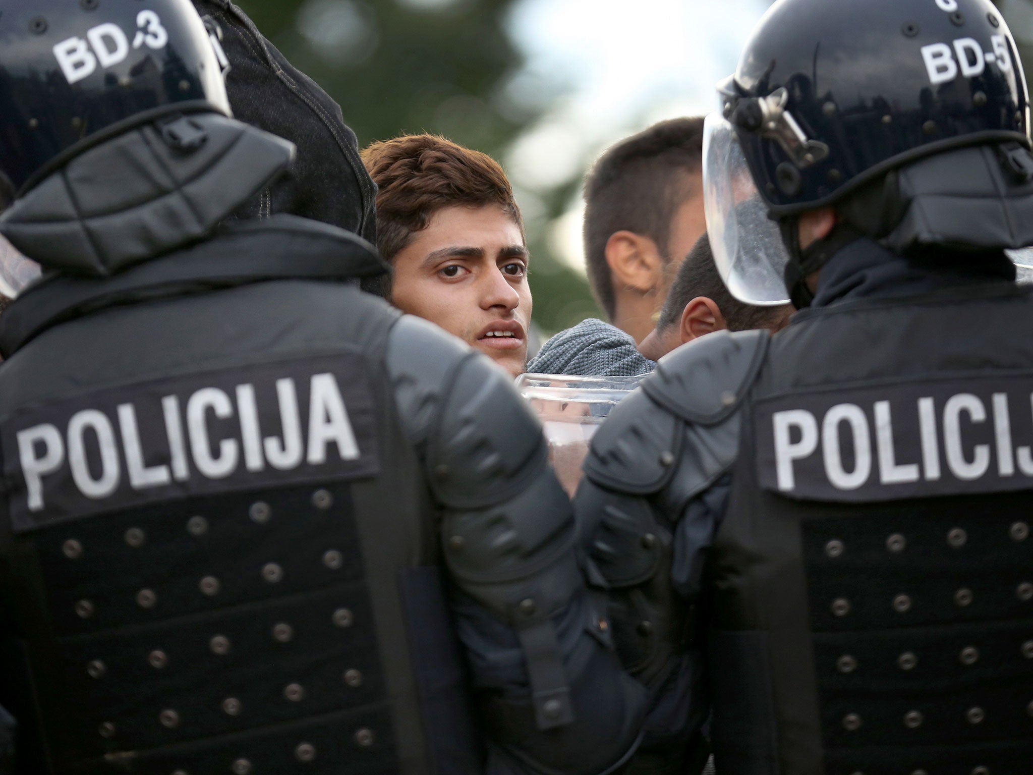 Refugees are held back by Slovenian riot police at the border in the small Croatian village of Harmica