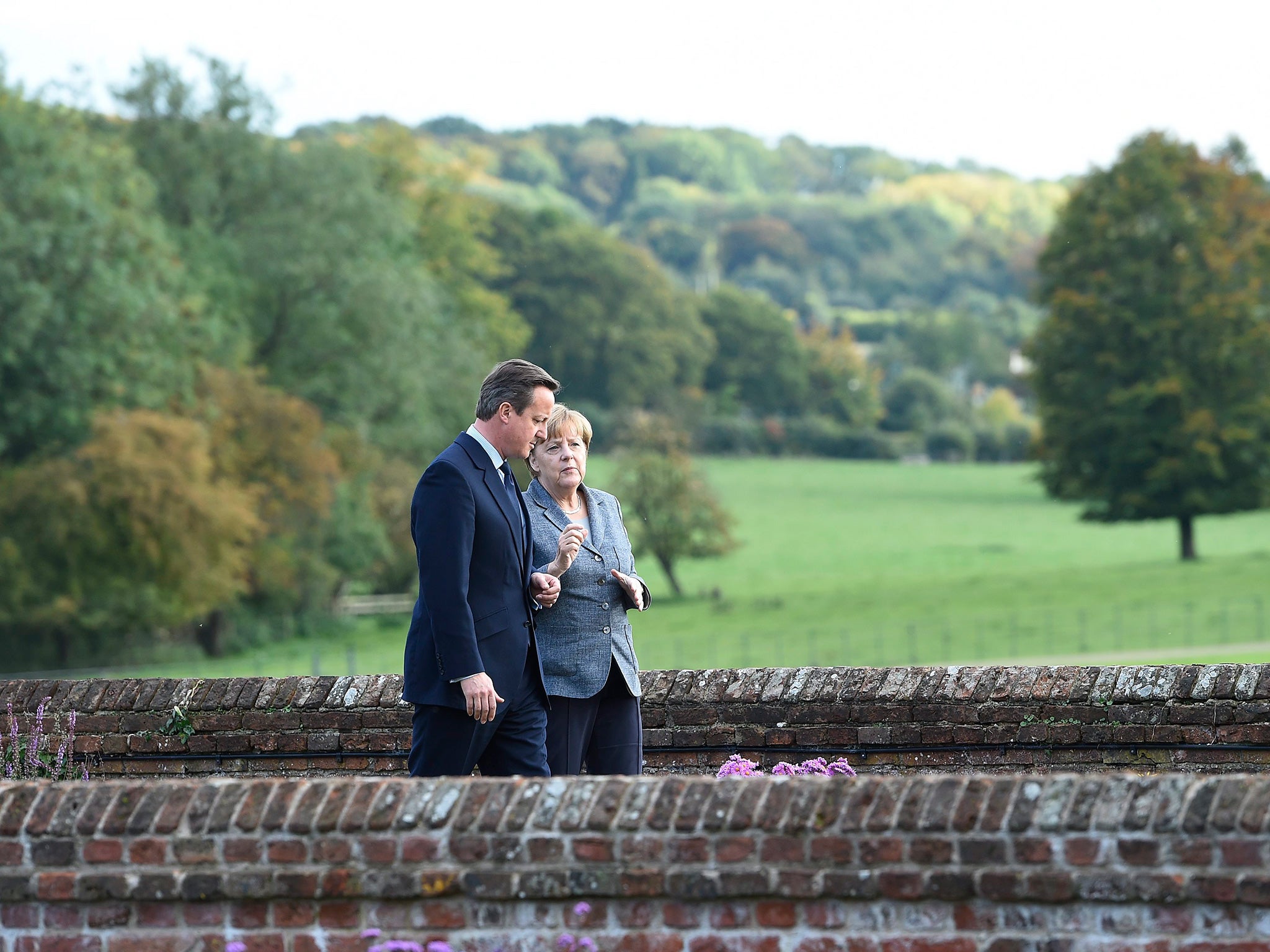 British Prime Minister David Cameron (L) and German Chancellor Angela Merkel (R) chat in the Rose Garden at Chequers in Ellesborough
