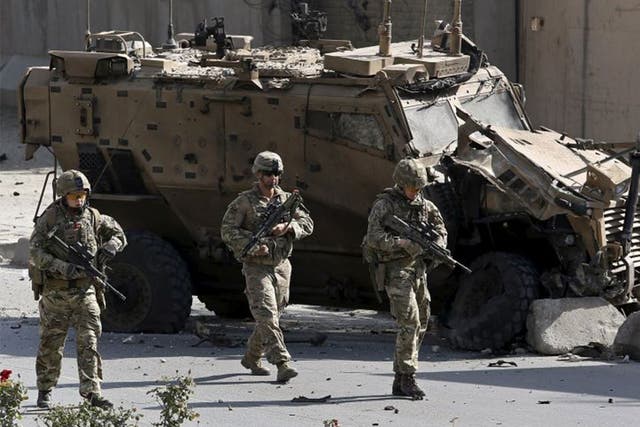 Nato soldiers walk in front of a damaged Nato military vehicle at the site of a suicide car bomb blast in Kabul