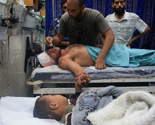 File: Medical teams treat a man and small boy in Gaza after a house is bombed