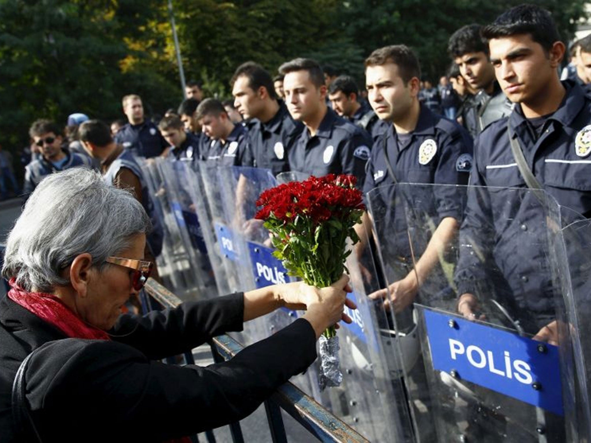 A demonstrator holds flowers before a police barricade during a commemoration for the victims of Saturday's bomb blasts in the Turkish capital, in Ankara, Turkey, October 11, 2015.