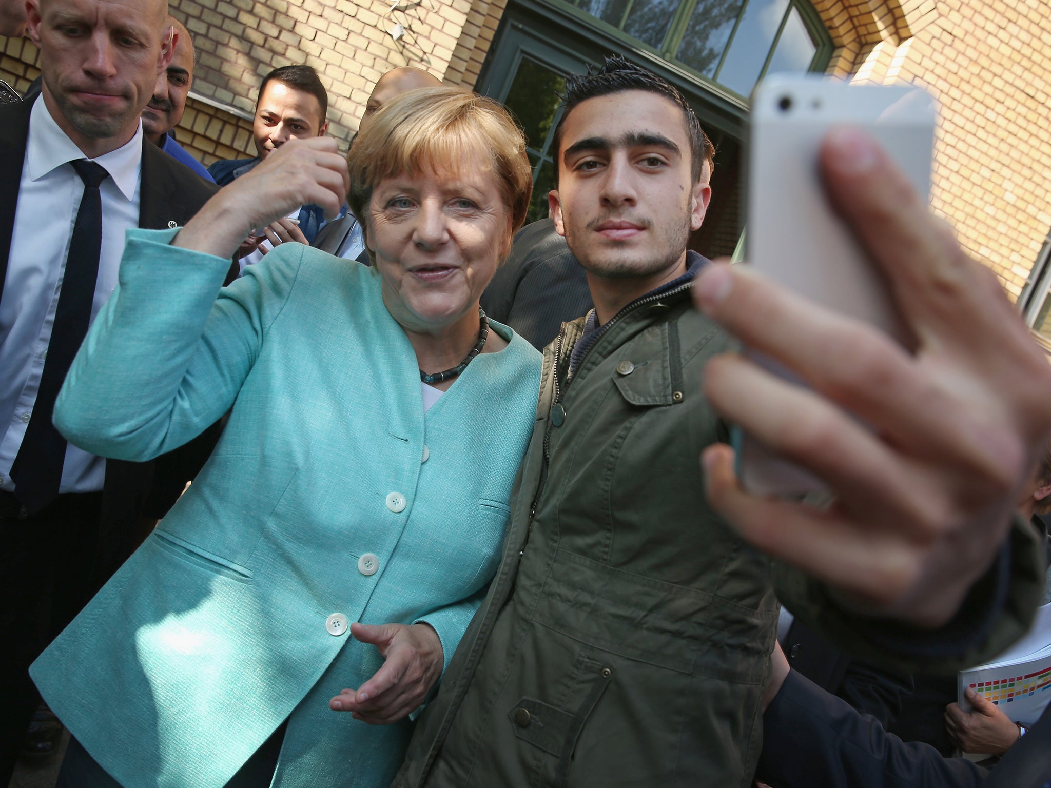Angela Merkel denies that this ‘selfie’ with a migrant, taken at a shelter outside Berlin, has been encouraging ‘hundreds of thousands of people to leave their homes and embark on this difficult road’