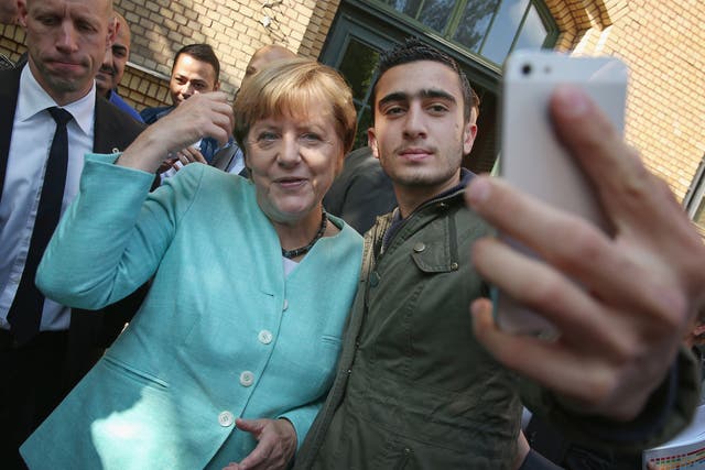 Angela Merkel denies that this ‘selfie’ with a migrant, taken at a shelter outside Berlin, has been encouraging ‘hundreds of thousands of people to leave their homes and embark on this difficult road’
