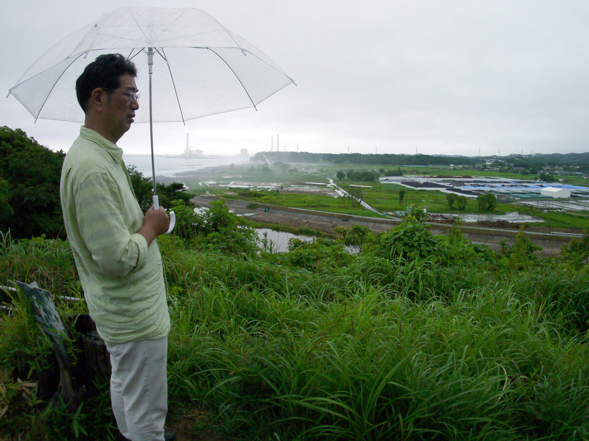 Satoru Yamauchi looking at the collection site of contaminated earth from a beachside park, in his hometown of Naraha, a tiny town in Fukushima prefecture