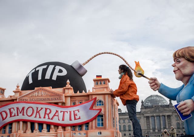 Activists work on a float showing Angela Merkel lighting a TTIP-bomb during a demonstration in Berlin, 9 October 2015