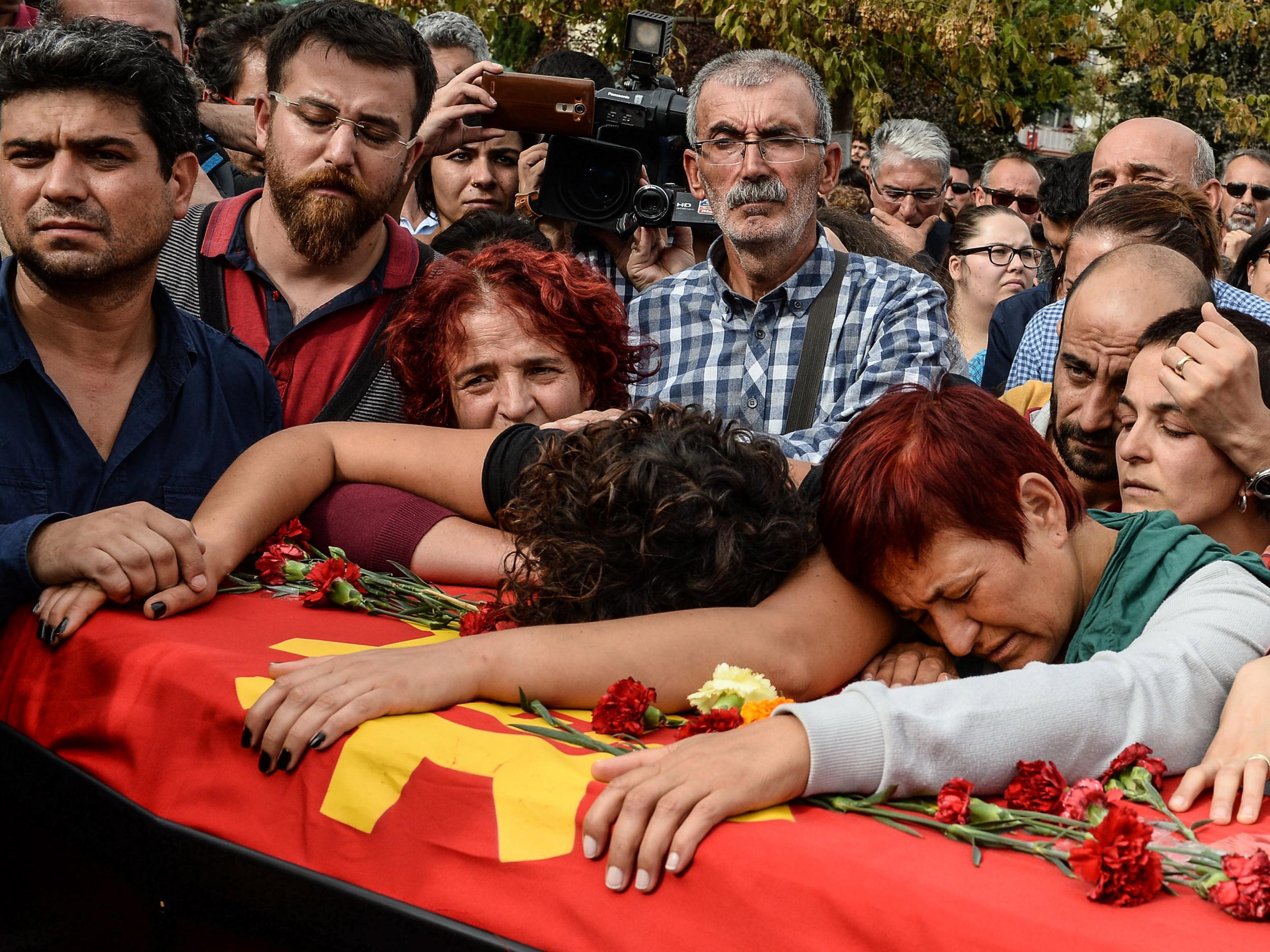 The family of one of the bombing victims mourn over his coffin at funeral in Ankara