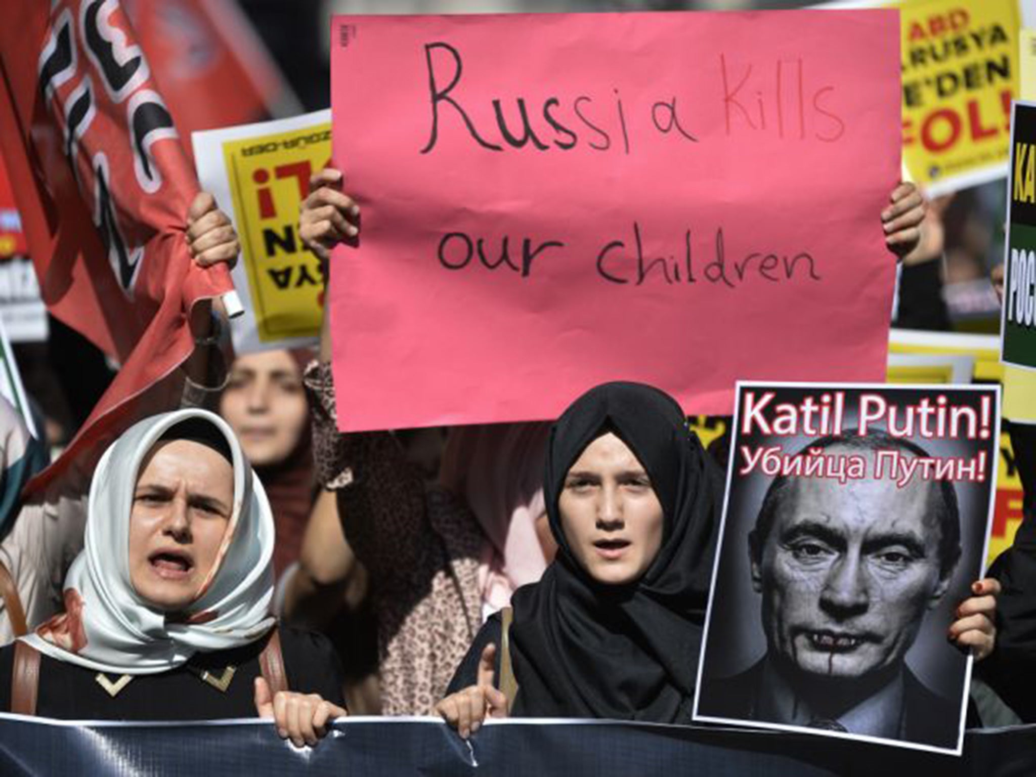 Demonstrators hold placards and a picture depicting Russian President Vladimir Putin during a protest against Russian military operations in Syria, in Istanbul