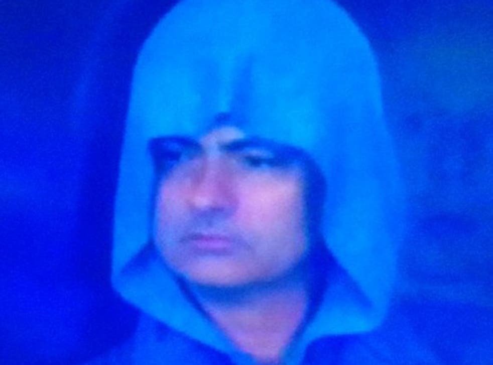 The hooded Jose Mourinho watches from the stands