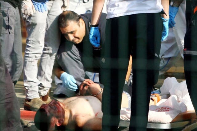 Israeli security forces stand next to a wounded and handcuffed Palestinian man who carried out the stabbing attack