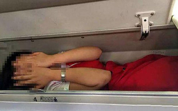 A cabin crew member apparently in an overhead locker