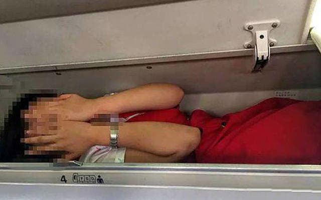 A cabin crew member apparently in an overhead locker