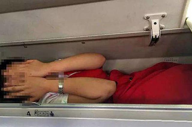 A cabin crew member apparently in an overhead locker