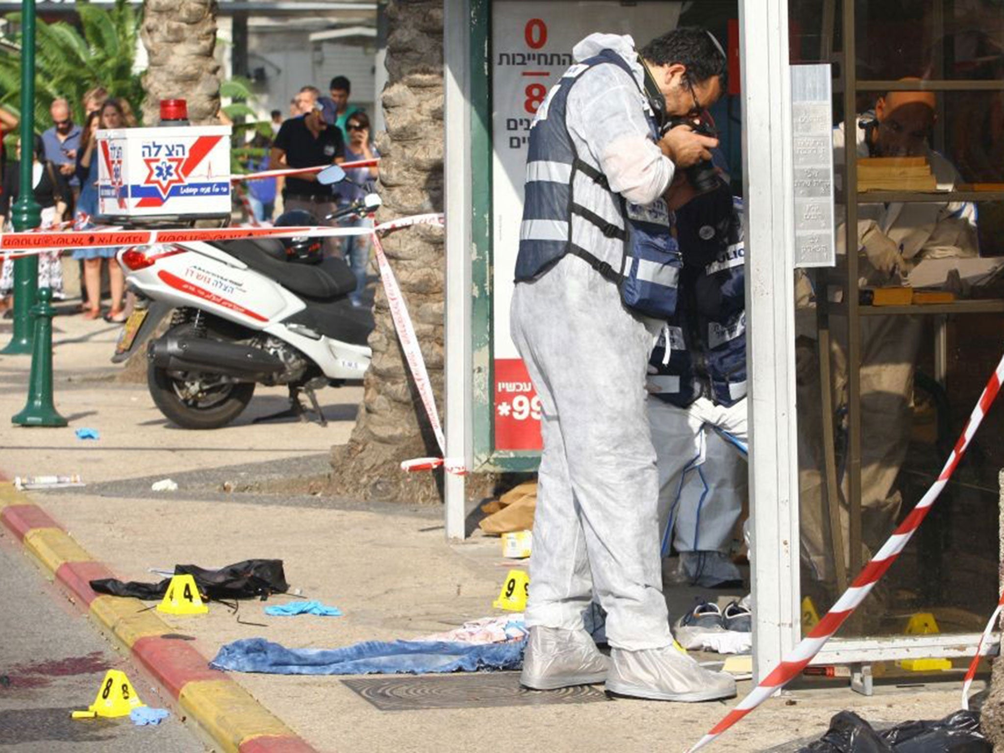 Israeli forensic experts inspect the scene of a stabbing attack carried out by a Palestinian man in the Israeli city of Raanana on October 13, 2015.