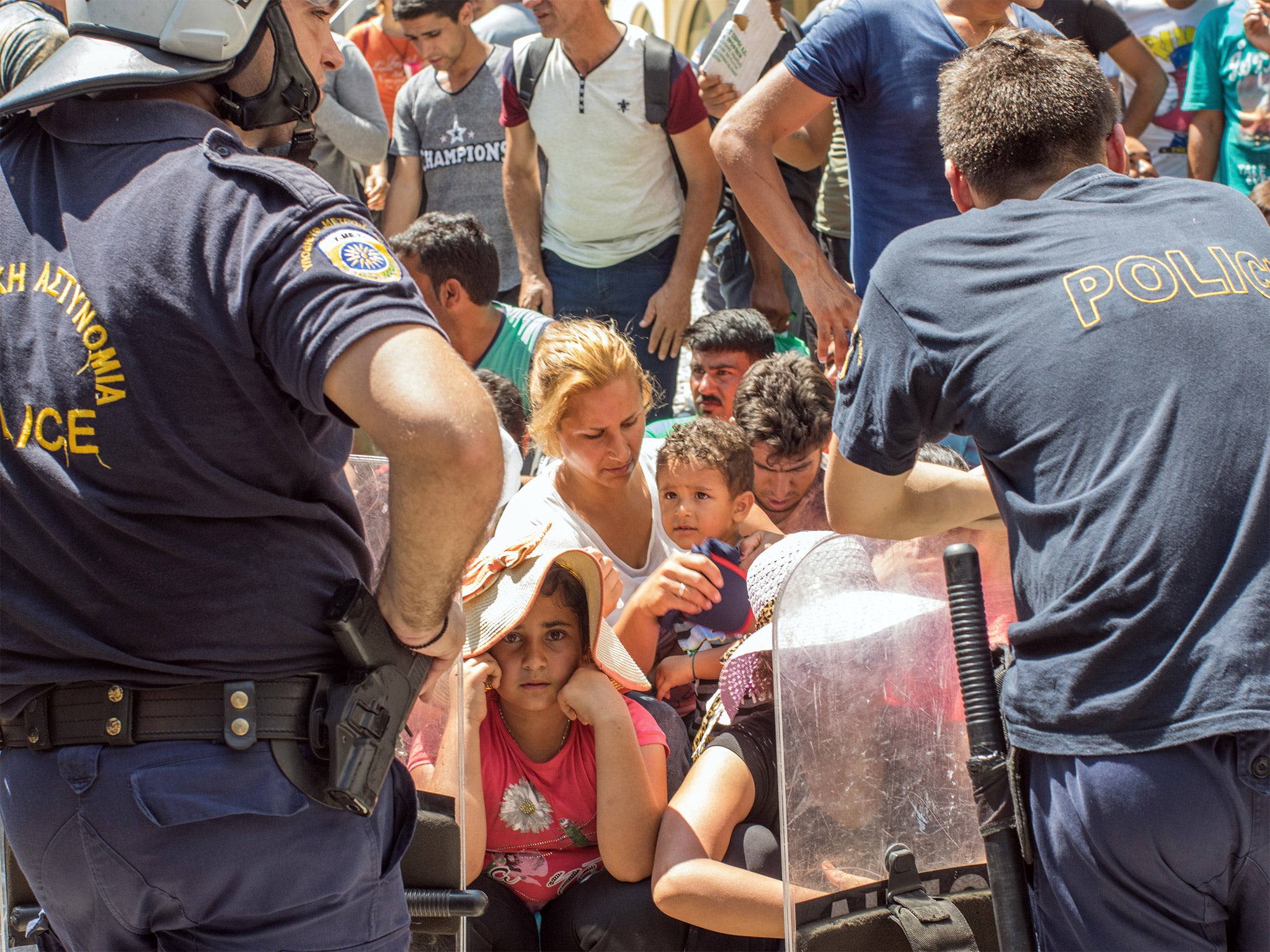 Refugees wait outside a police station in Kos