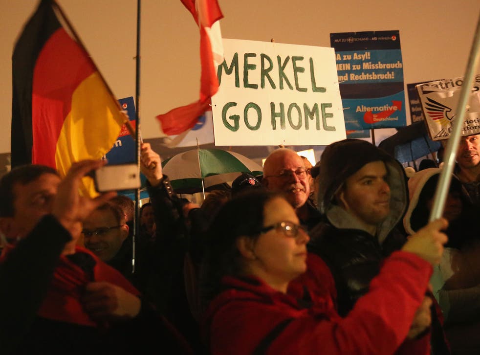 Supporters of the AfD political party protest against German Chancellor Angela Merkel's liberal policy towards taking in migrants and refugees on October 14, 2015 in Magdeburg, Germany