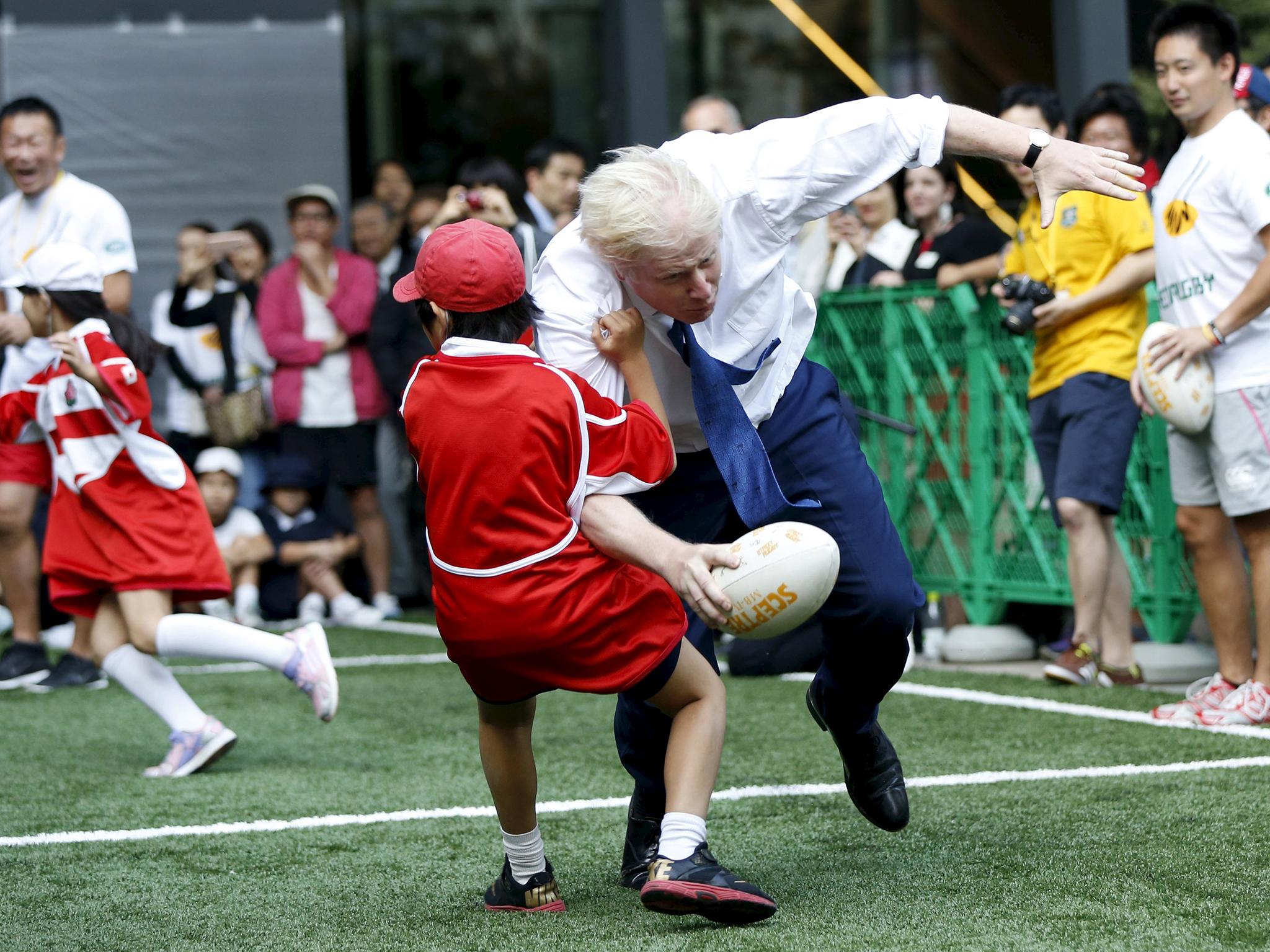 &#13;
Boris Johnson collides with a 10-year-old boy during a game of street rugby in Tokyo in 2015 &#13;