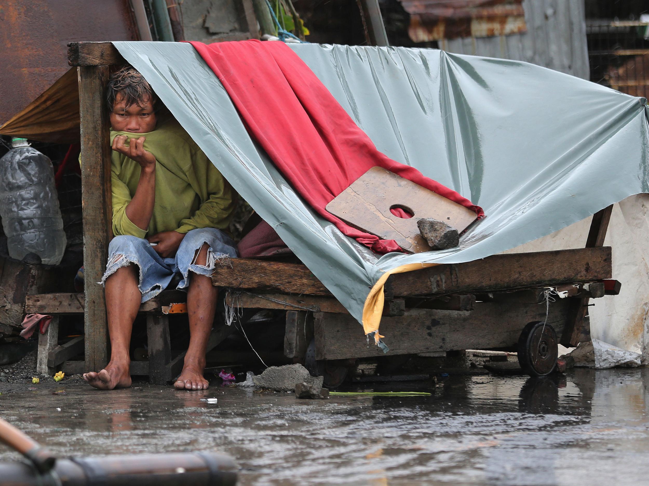 A Filipino man sits inside his makeshift home as Typhoon Koppu hits the coastal town of Navotas, north of Manila AP