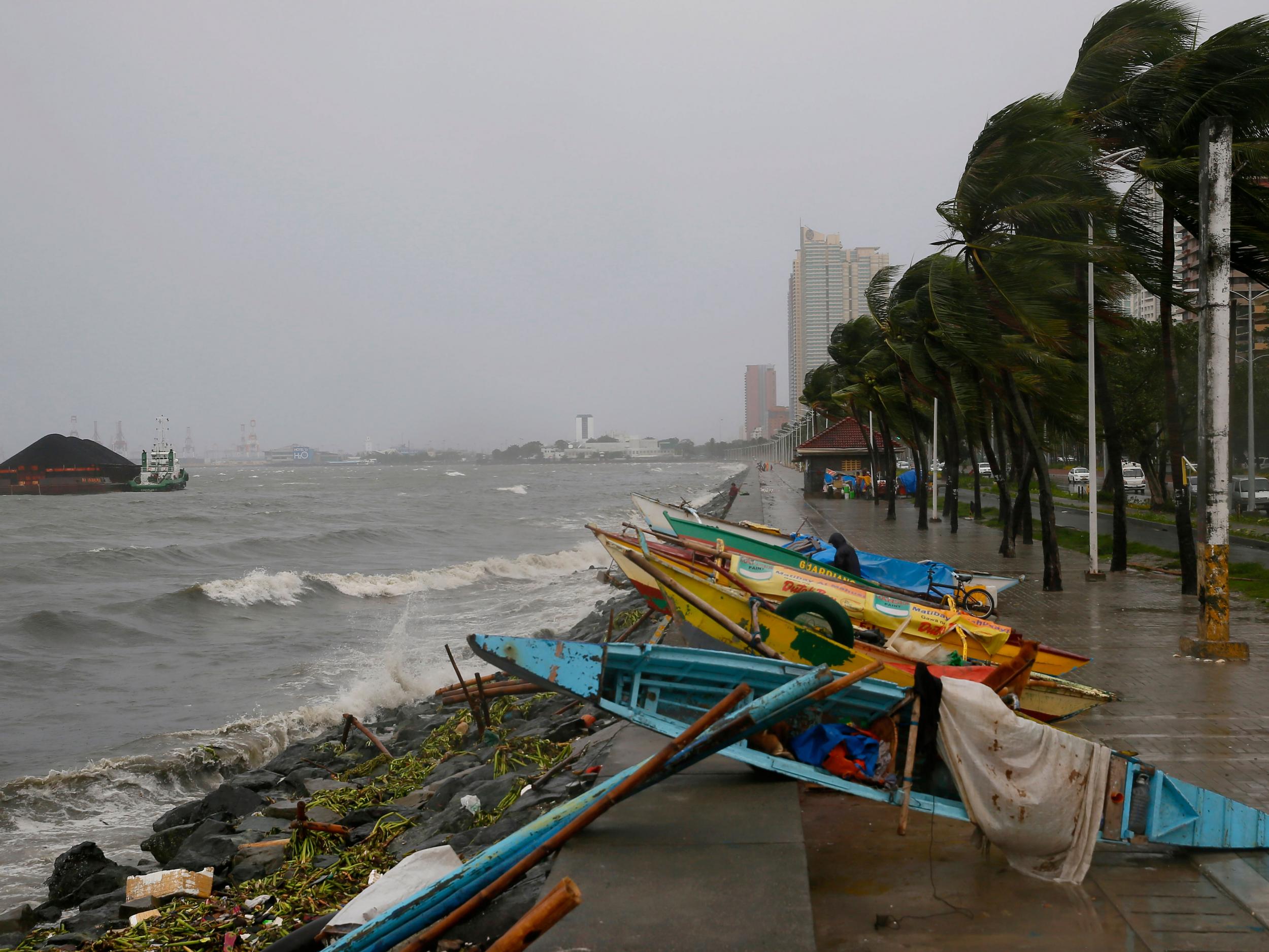 Small fishing boats are placed by the seawall as strong winds hit Manila AP