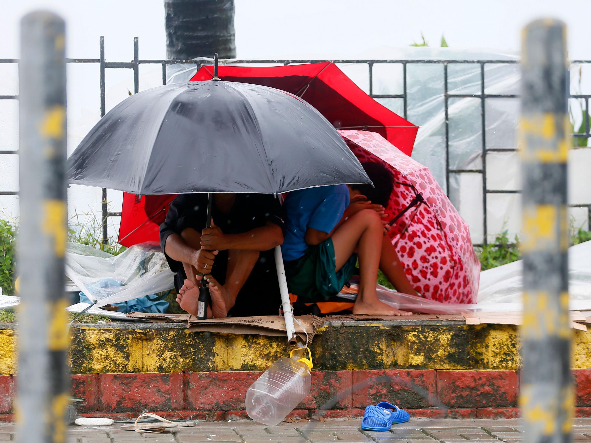 Residents huddle together under their umbrellas as strong winds are brought by Typhoon Koppu AP