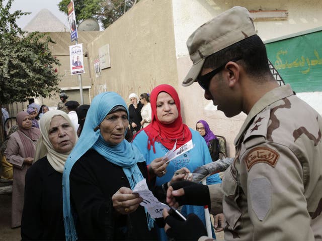 An Egyptian army officer checks documents of voters outside a polling station during the first round of parliamentary elections, in Giza, Cairo