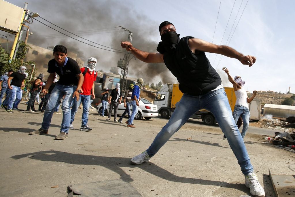 Palestinian protesters throw stones during clashes with Israeli security forces in the West Bank city of Hebron this morning