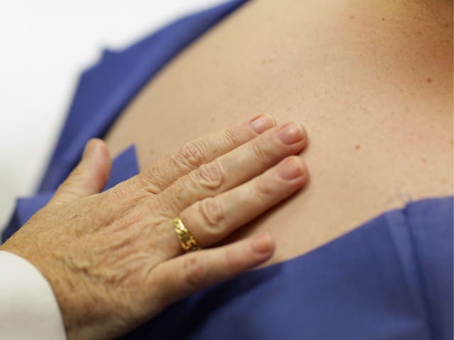 A doctor examines a patient for symptoms of skin cancer