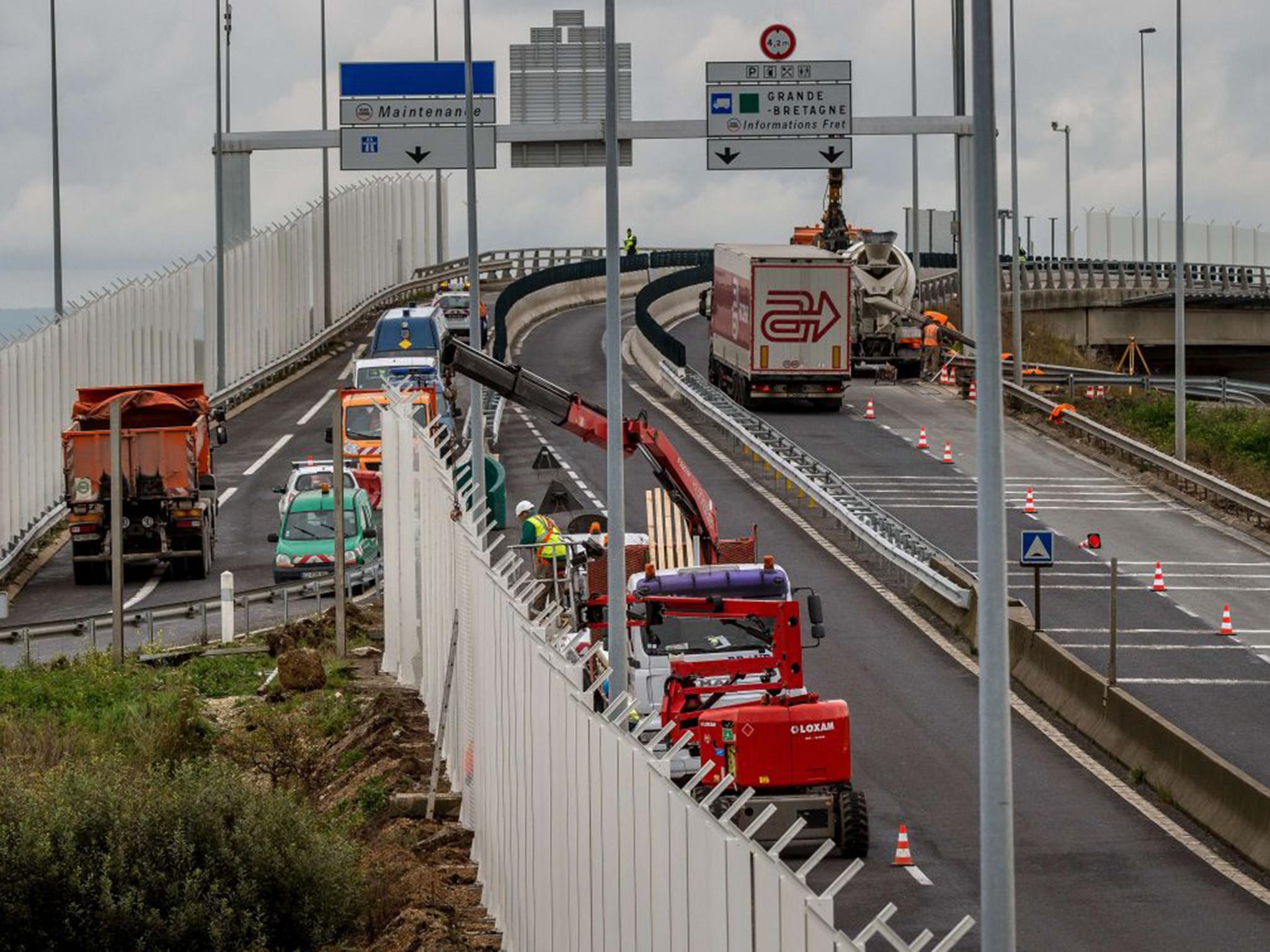 Workers install seven-metre high fencing along the access route to the Eurotunnel in Coquelles to try and prevent migrants from attempting to cross the Channel to Britain