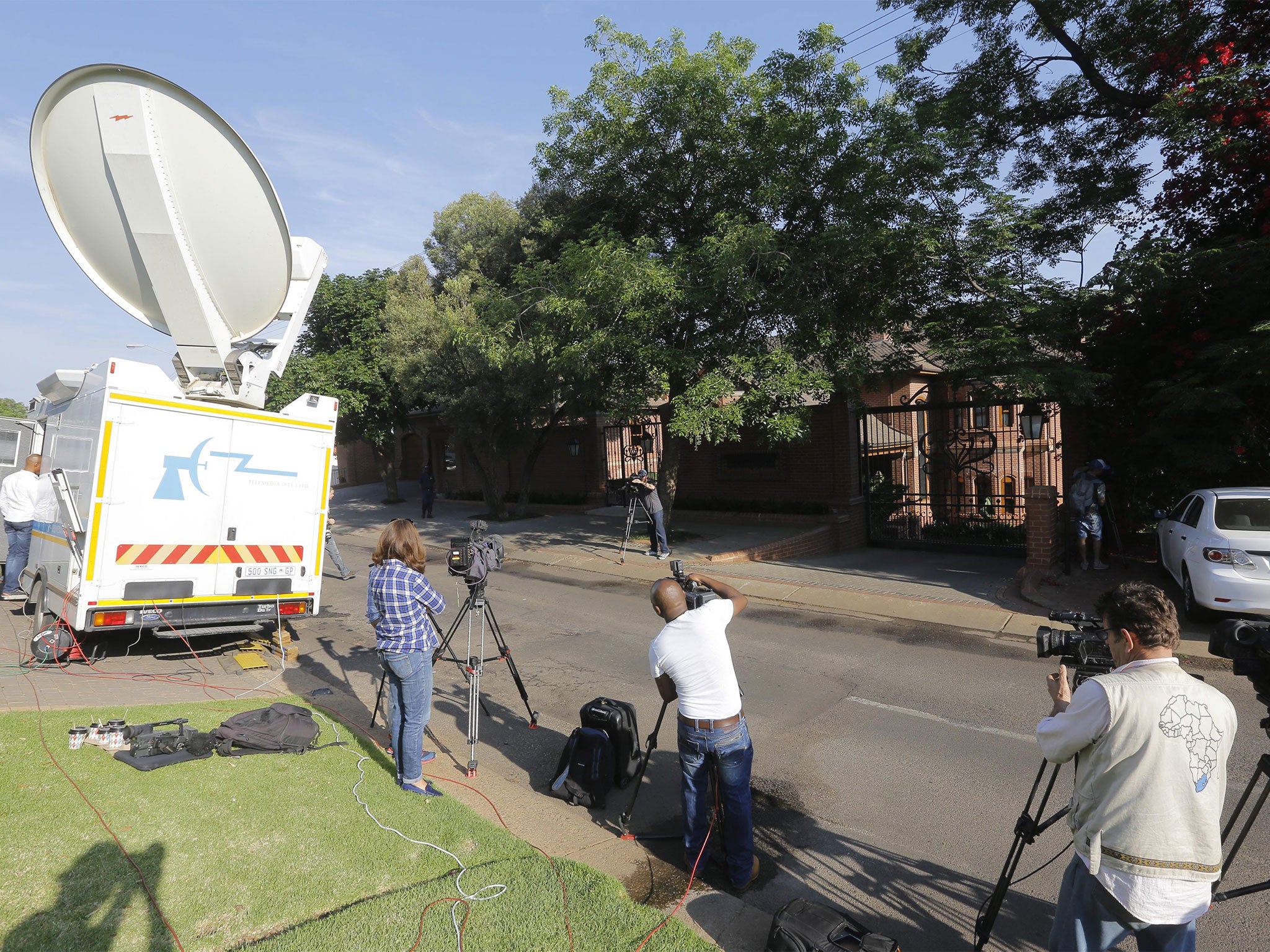 Media wait outside the home of Pistorius' uncle, where he is believed to be serving his house arrest