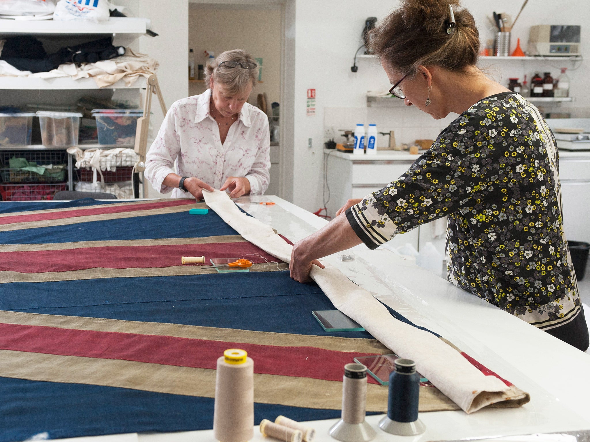Conservators at work on the Union flag that survived the Battle of Trafalgar