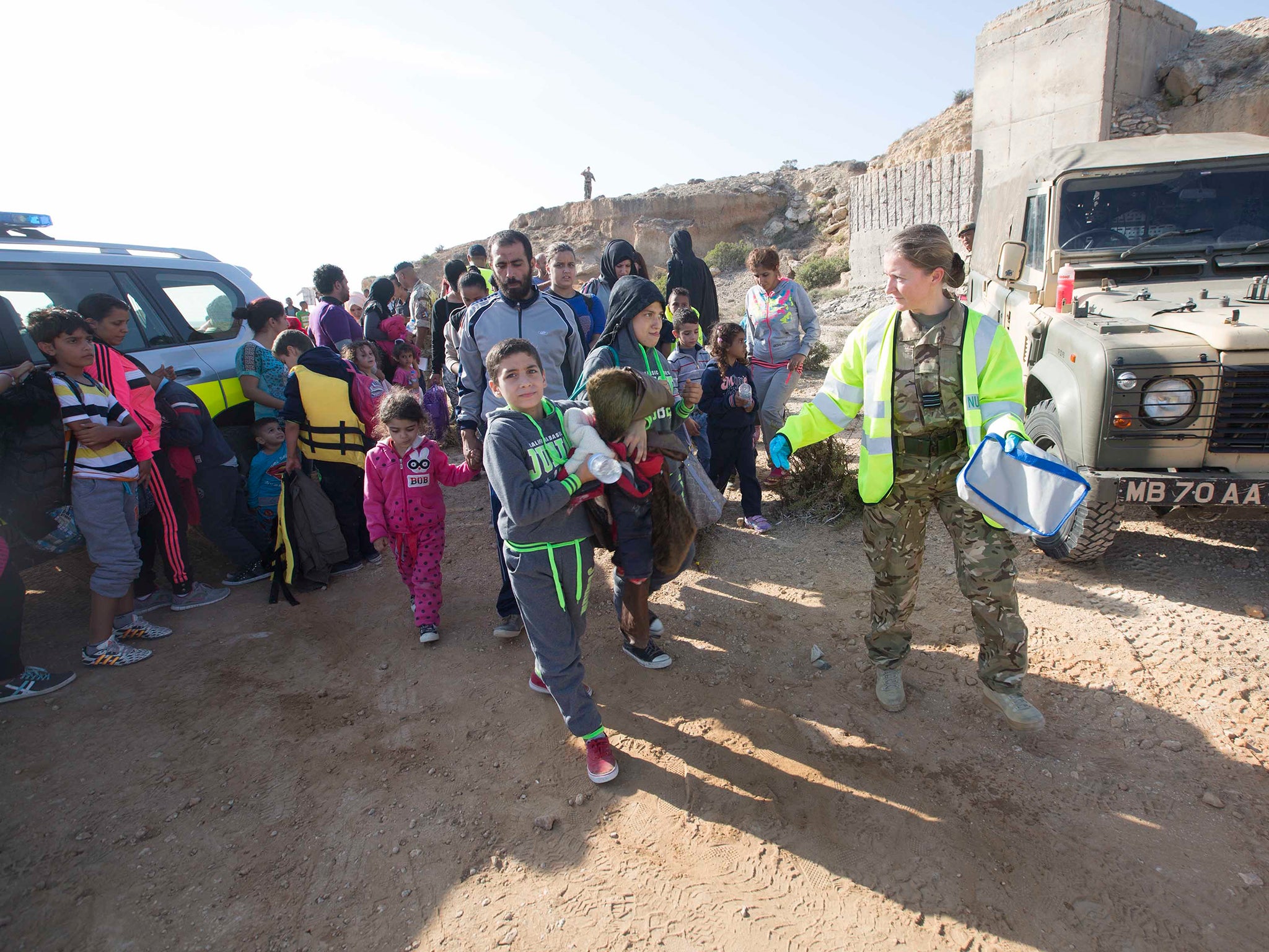 Armed forces personnel speaking to some of the refugees that were on four boats that landed at the RAF air base at Akrotiri in Cyprus