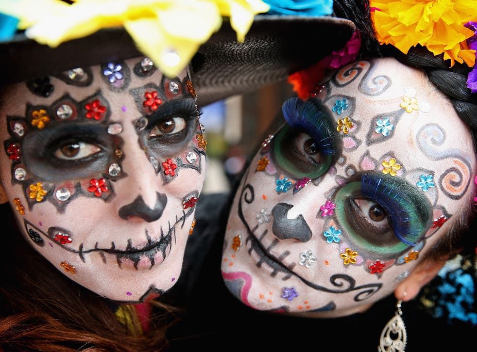 People dress up in vibrant colours and paint their faces to look like skulls during the celebration